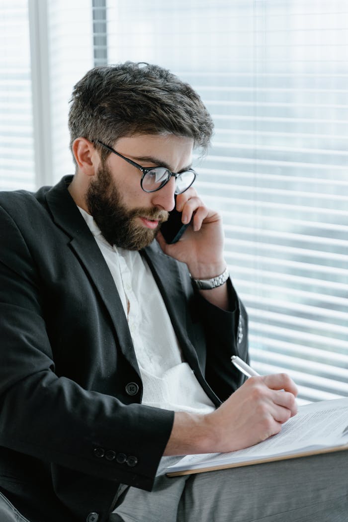 Mastering the First Impression: Your intriguing post title goes here Focused businessman in office, analyzing documents while on a phone call.